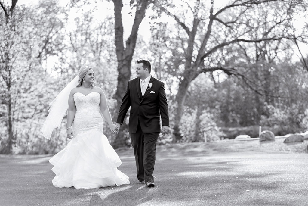 a wedding couple holding hands as they walk on a golf course in Morris