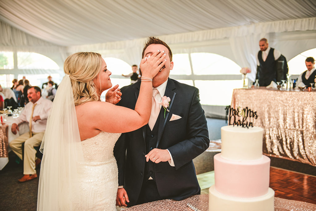 the bride stuffing cake in her grooms face at their wedding reception in Morris