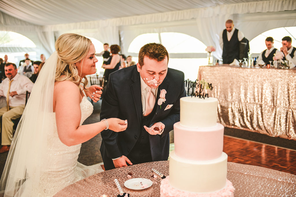 the bride laughing at the groom with cake all over his face after cutting their cake