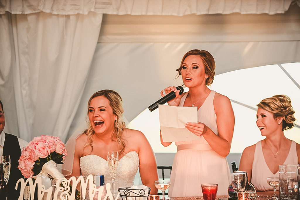 the bride laughing hard as the maid of honor reads her speech at a wedding reception in Morris