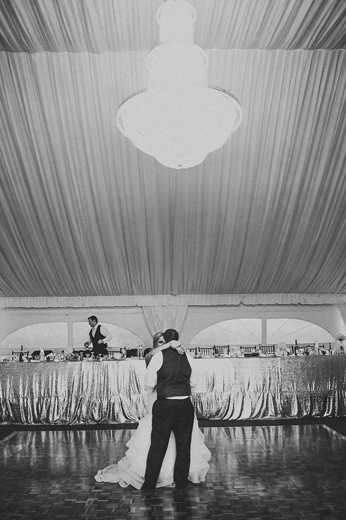 a beautiful chandelier illuminating a bride and groom as they dance during their first dance