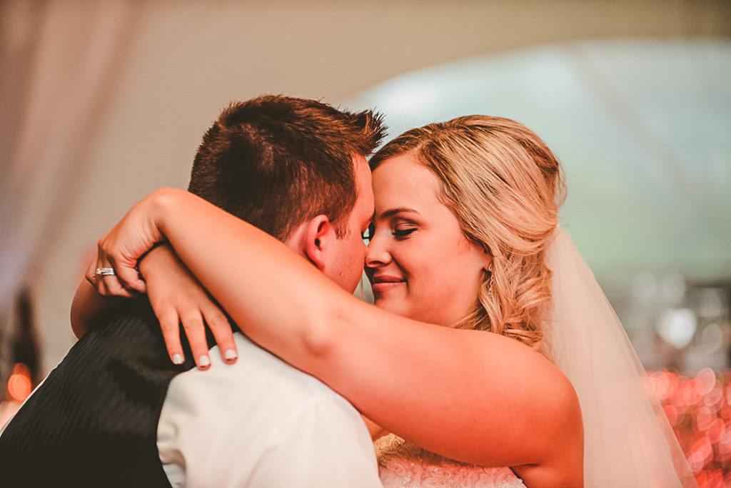 a bride and groom smiling as they kiss during their first dance at the Morris Country Club