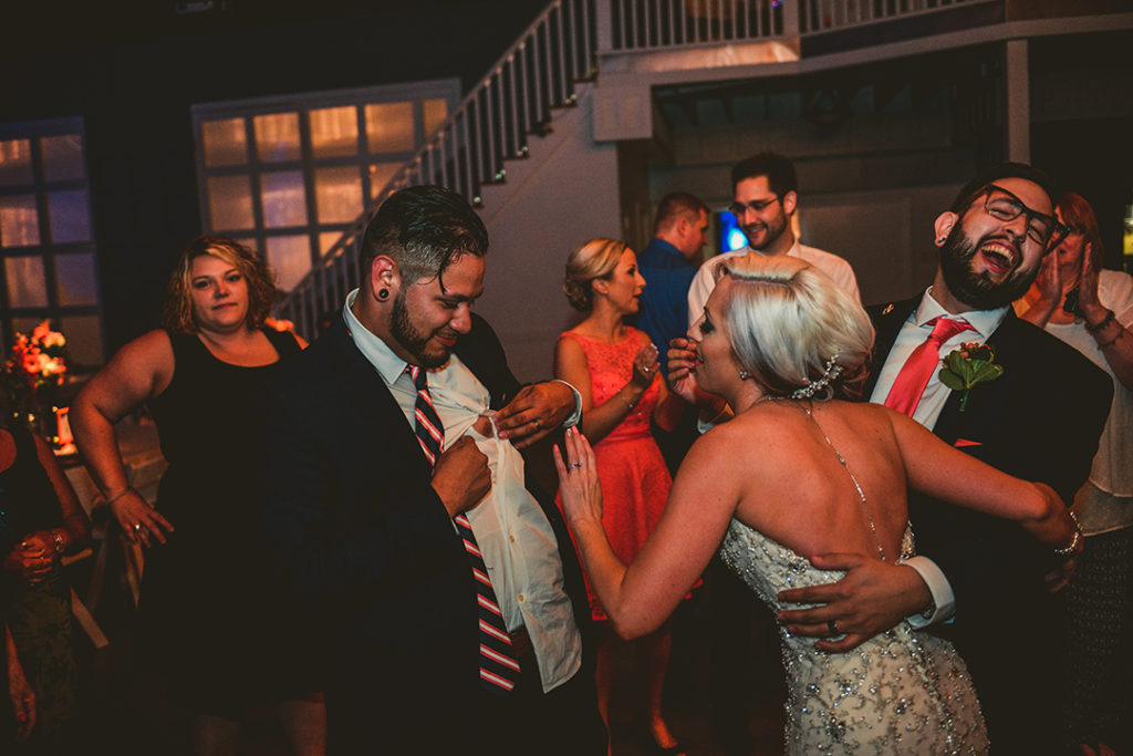 man showing his nipple at a wedding reception as the groom laughs