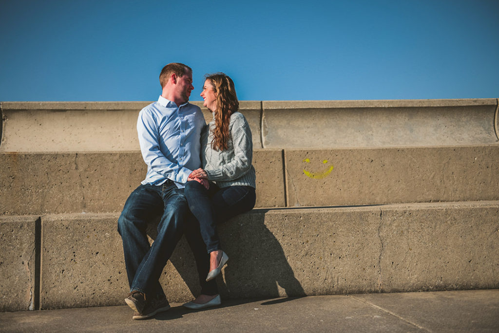 a couple sitting by Lake Michigan with a yellow smiley face next to them