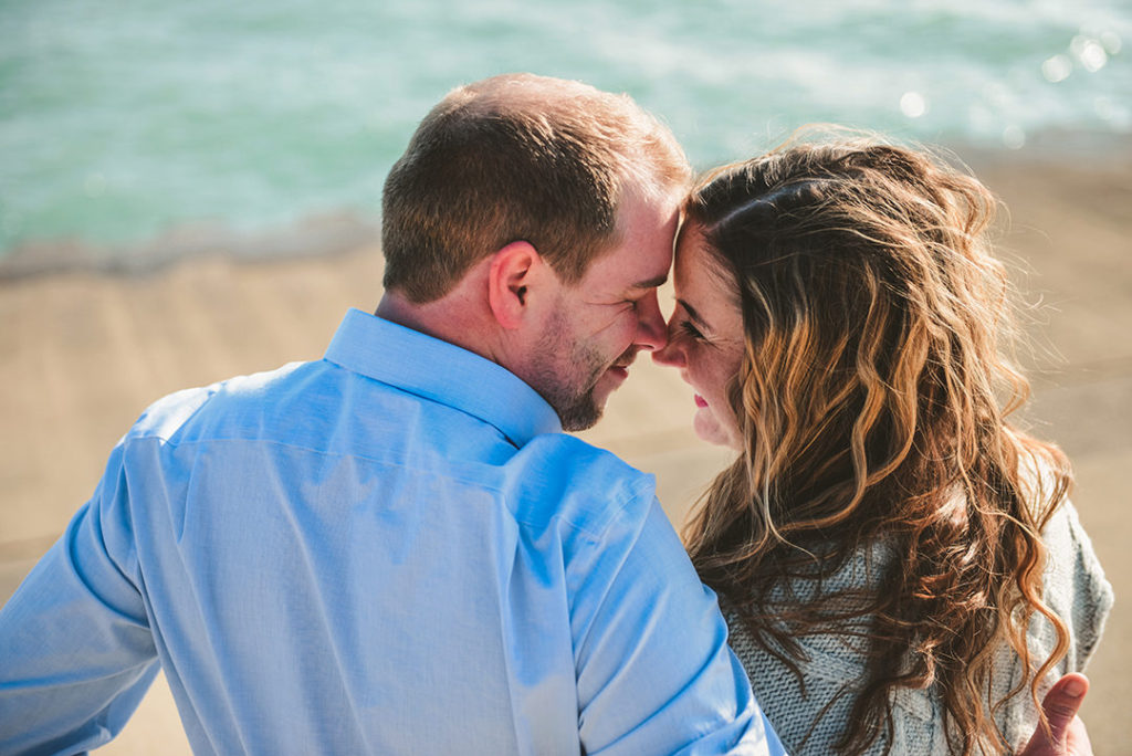 a cute couple touching noses as they sit by the Chicago lakefront