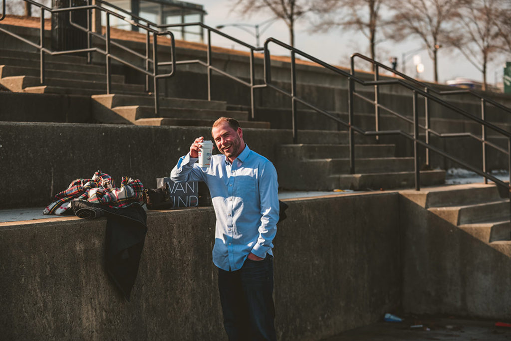 a man laughing as he drinks coffee on a engagement session in Chicago