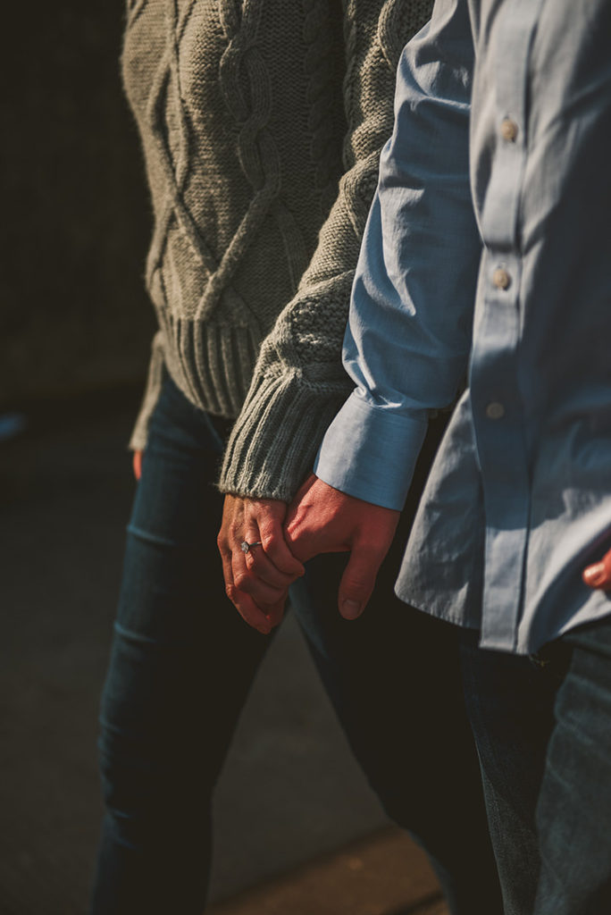 a woman holding her husbands hand as they walk showing off her beautiful ring