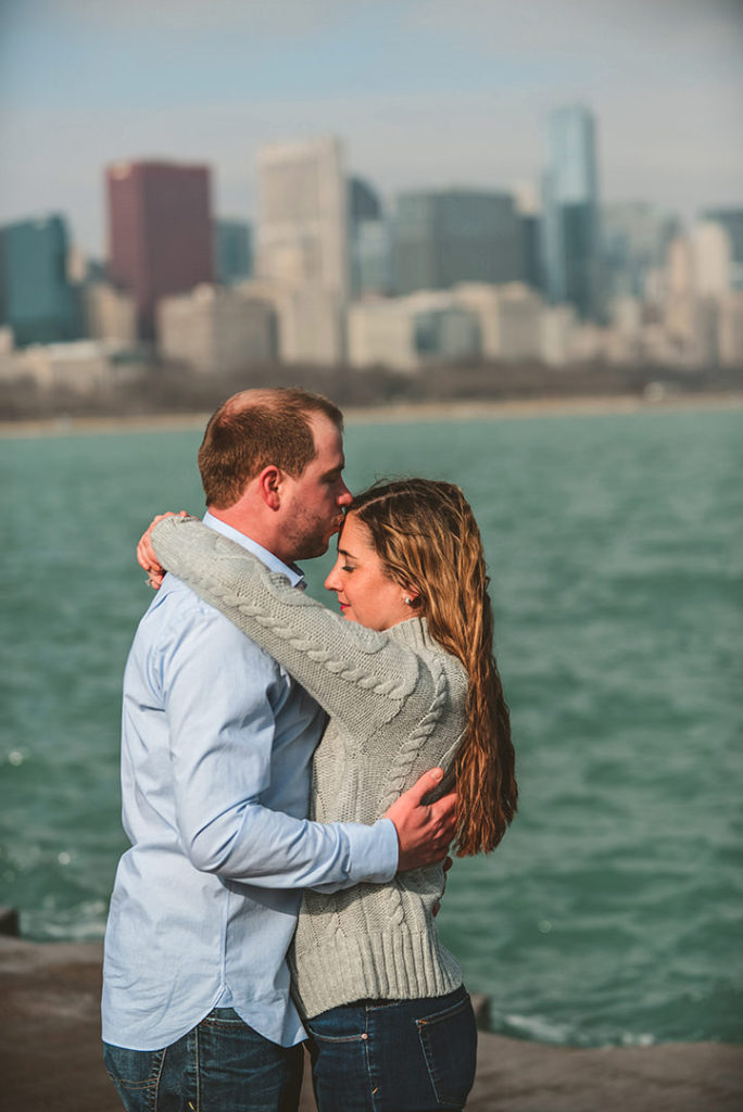a husband kissing his wives head in front of the Chicago skyline