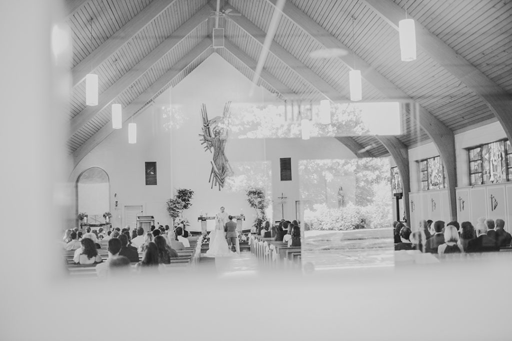 through a window of a church as a couple gets married at a church alter