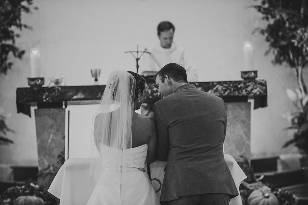 a wedding couple smiling as they look at each other at the alter of a church