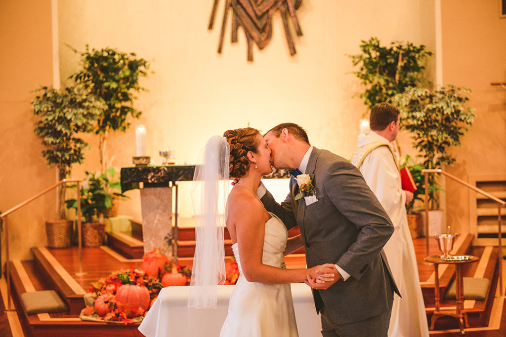 the bride and groom experiencing their first kiss at the church alter in the warm light