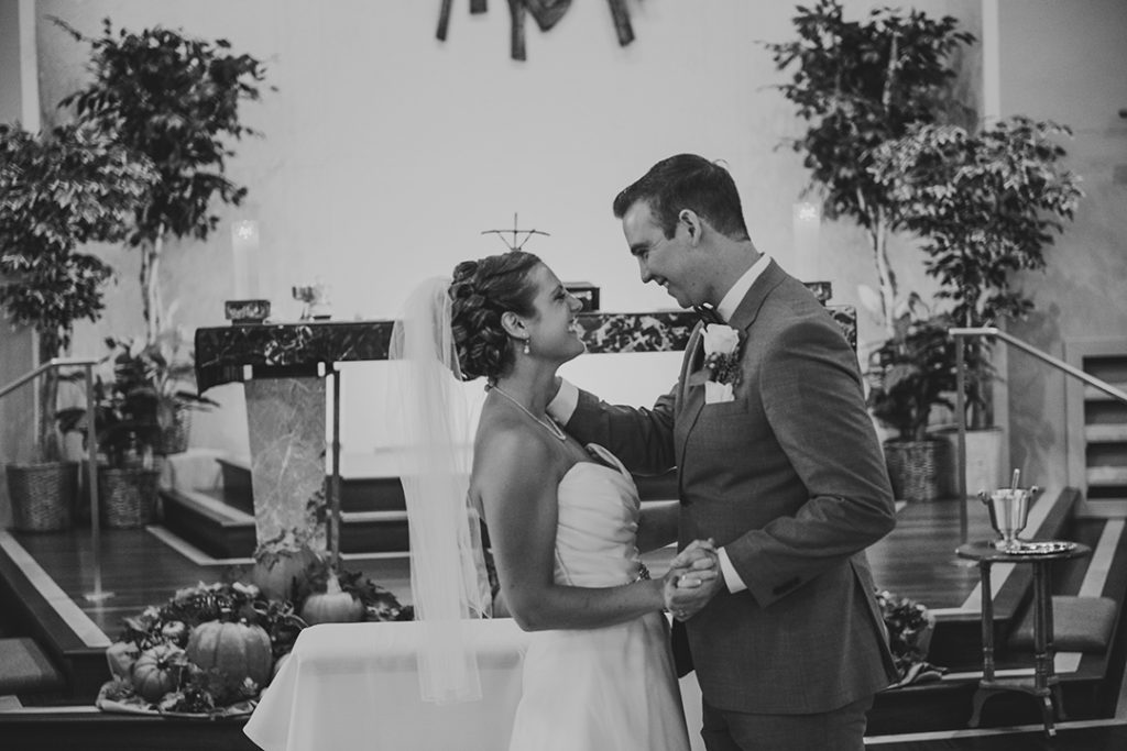 moments after a first kiss the bride and groom smiling at each other at the church alter