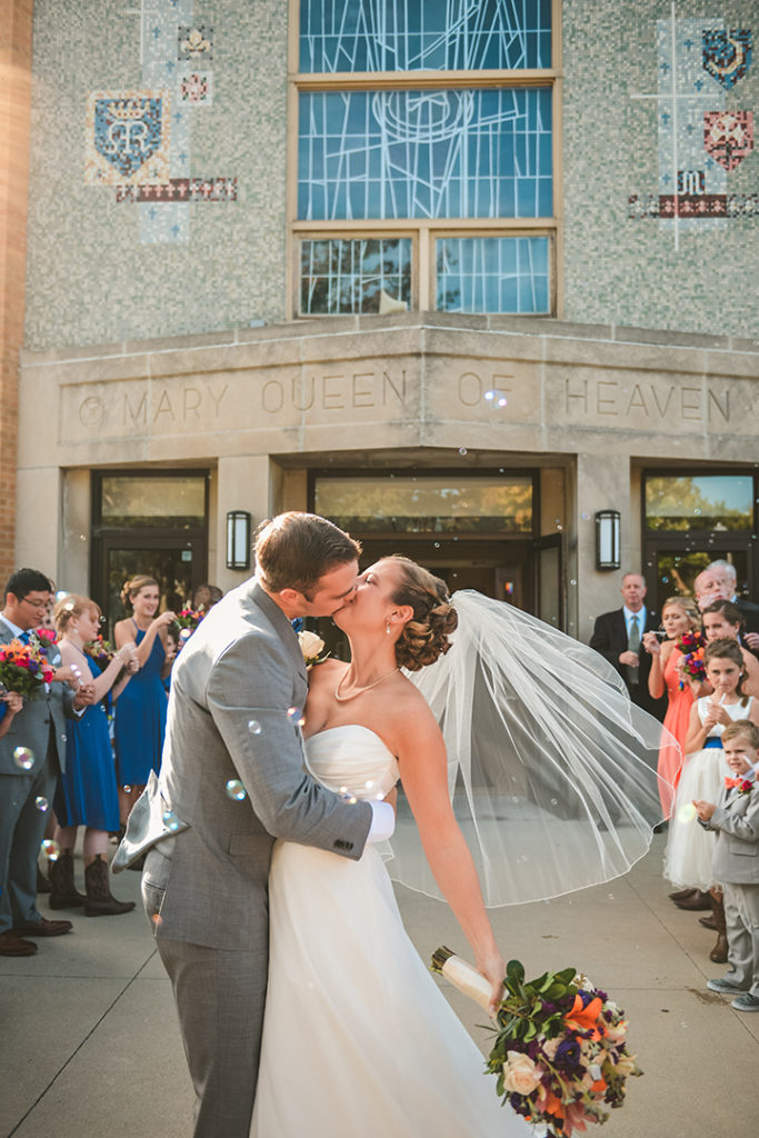 a newly married couple exiting Mary Queen of Heaven church to bubbles