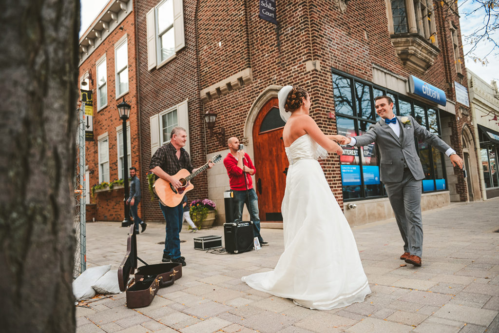 a wedding couple dancing in downtown Elmhurst in front of a brick building