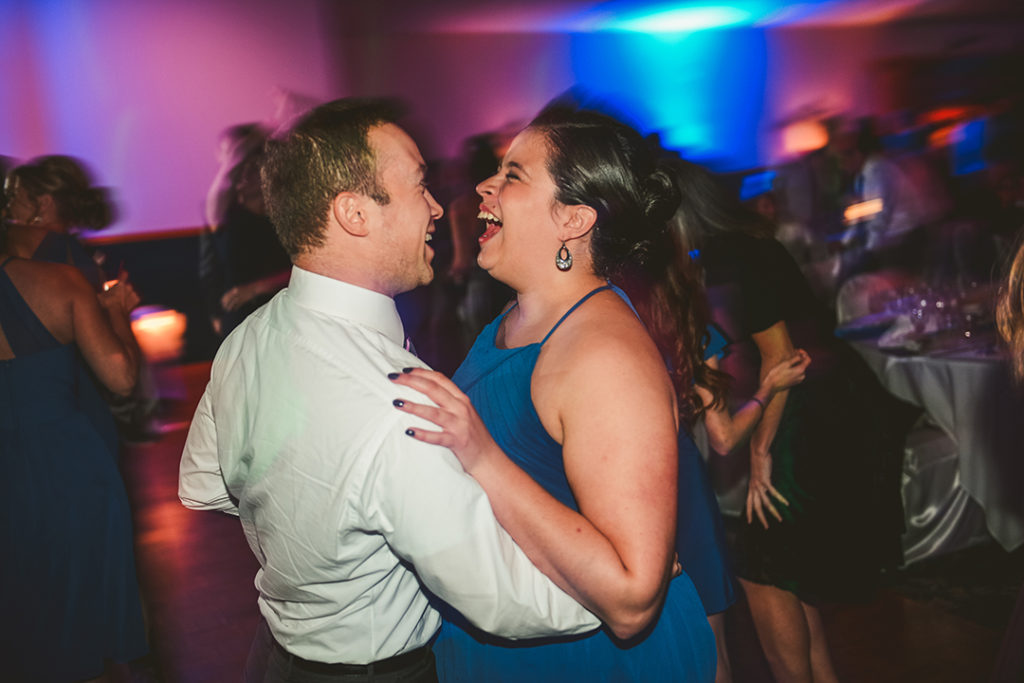 a man and a woman dancing with blue and pink lights in the background