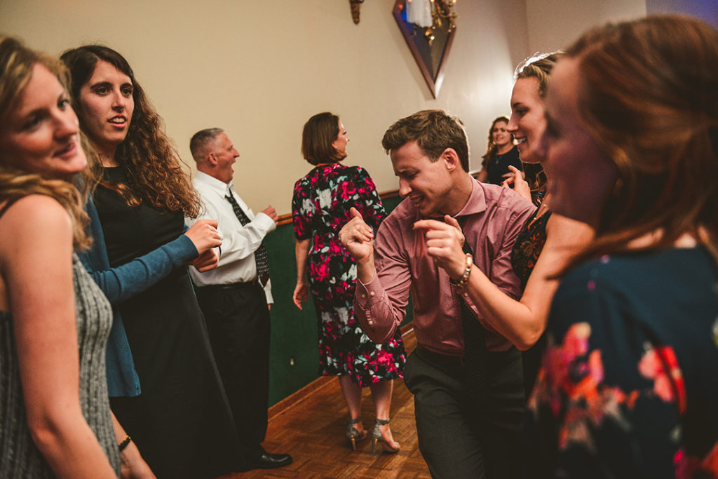 a group of wedding guests dancing at a wedding reception as they laugh