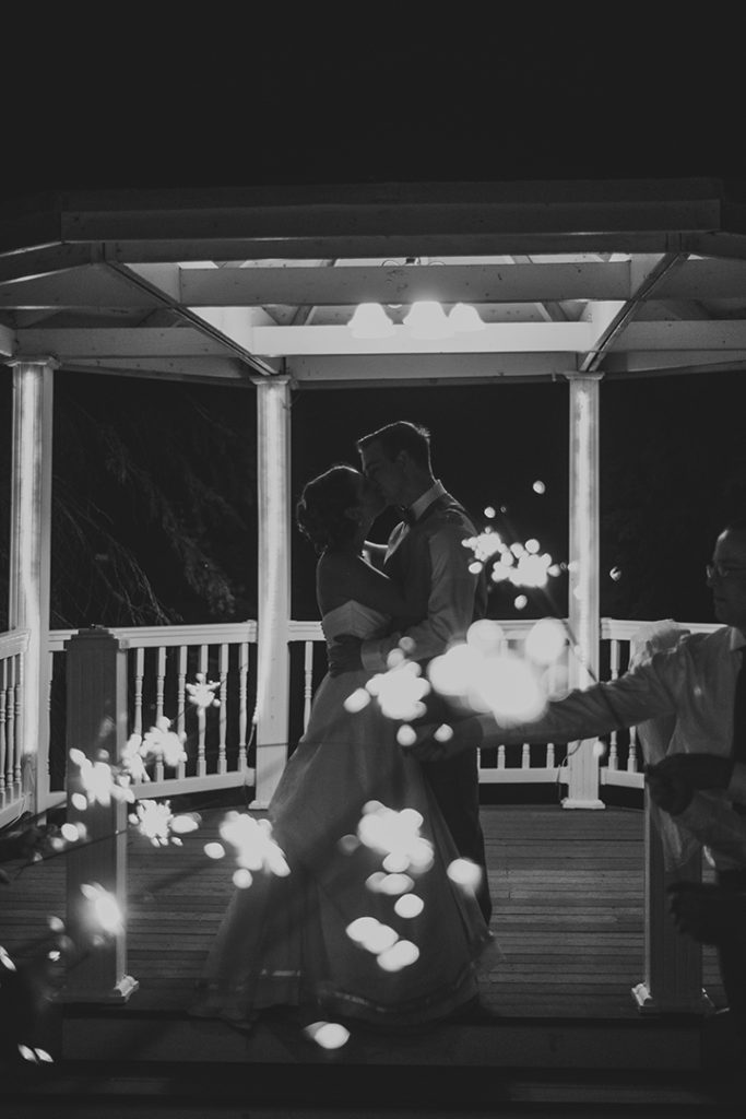 a couple kissing at night in front of sparklers in black and white