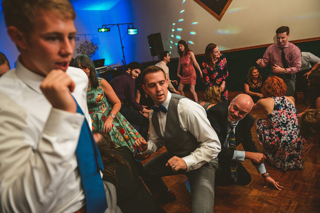 a groom getting low on a dance floor as everyone else dances