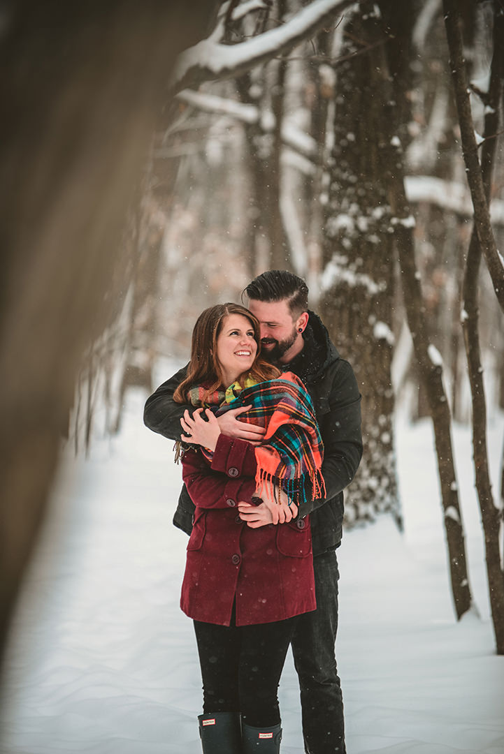 a engaged couple hugging in the snow at Hamel Woods