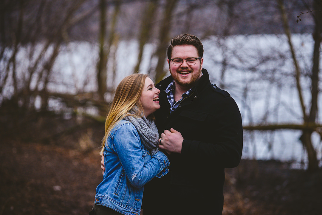 husband and wife hugging in the woods laughing