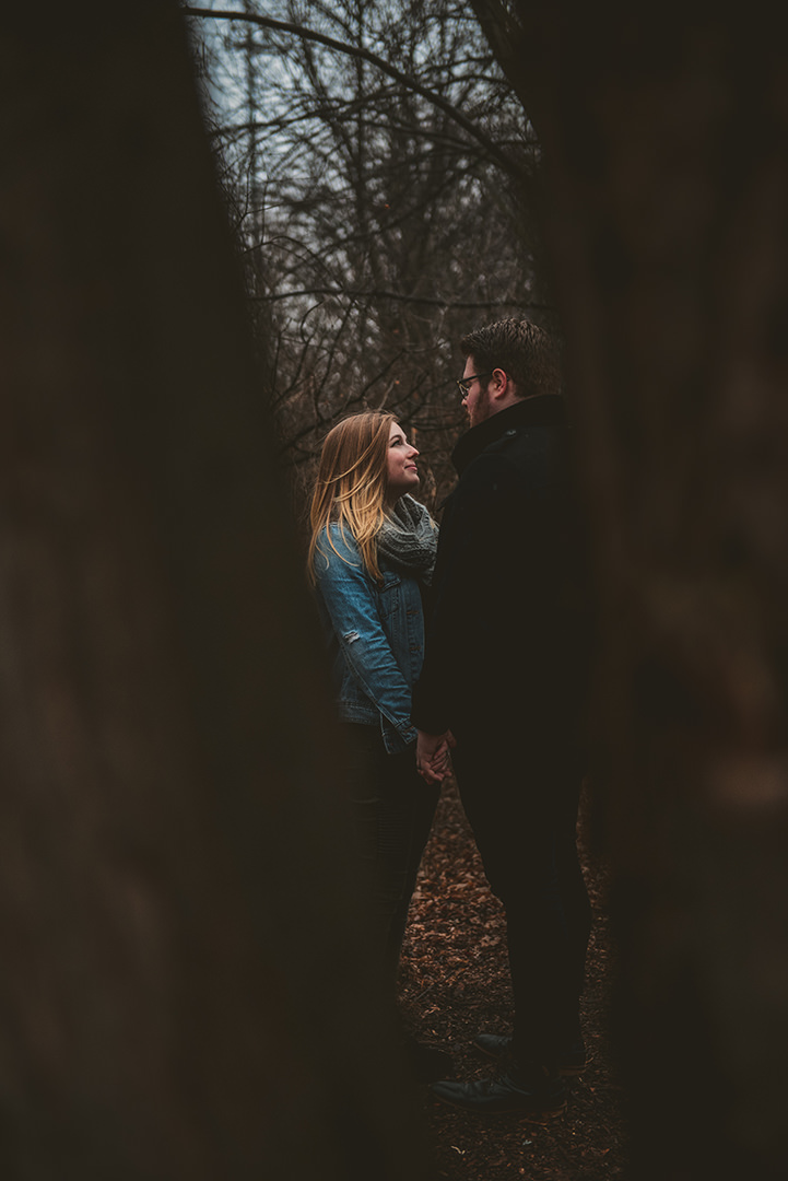 a man and a woman flirting in the woods as two trees frame them