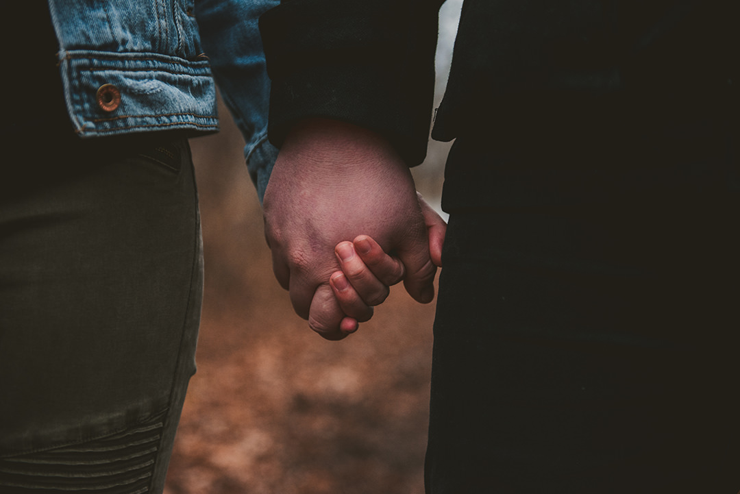 a closeup of a husband and wife holding hands