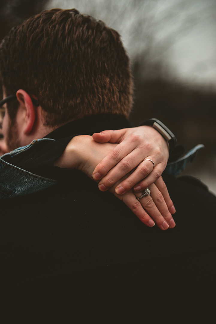 a closeup of a brides arms around her grooms neck