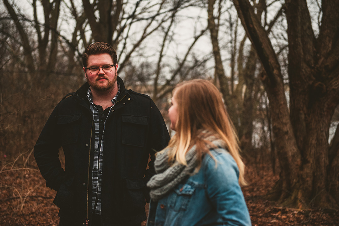 a man standing in the woods as his wife looks back at him