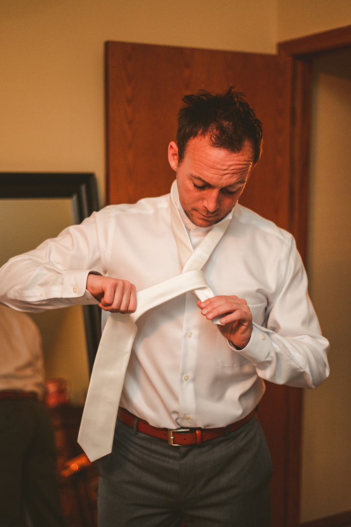 groom tying tie at childhood home