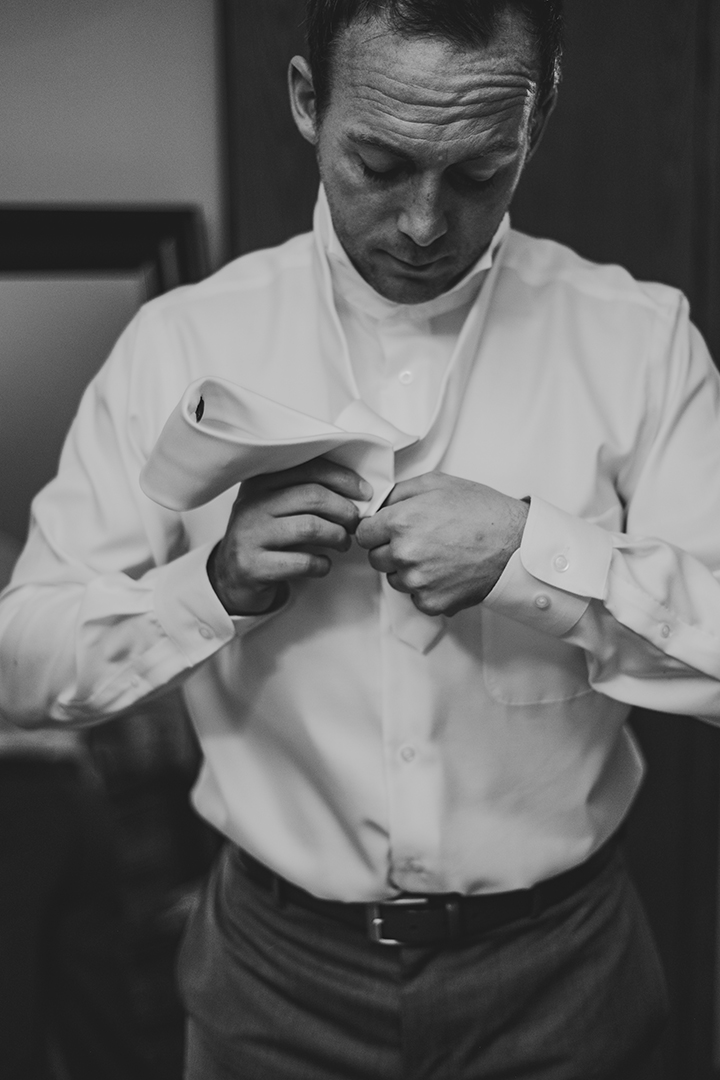 black and white image of groom tying his tie