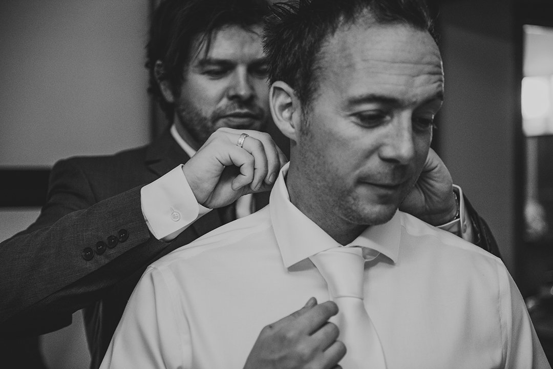 a groomsman helping the groom get ready