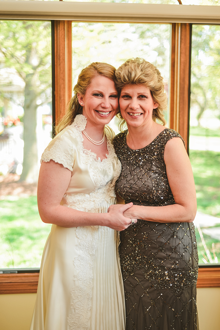 the bride and her mom hugging in front of a large window