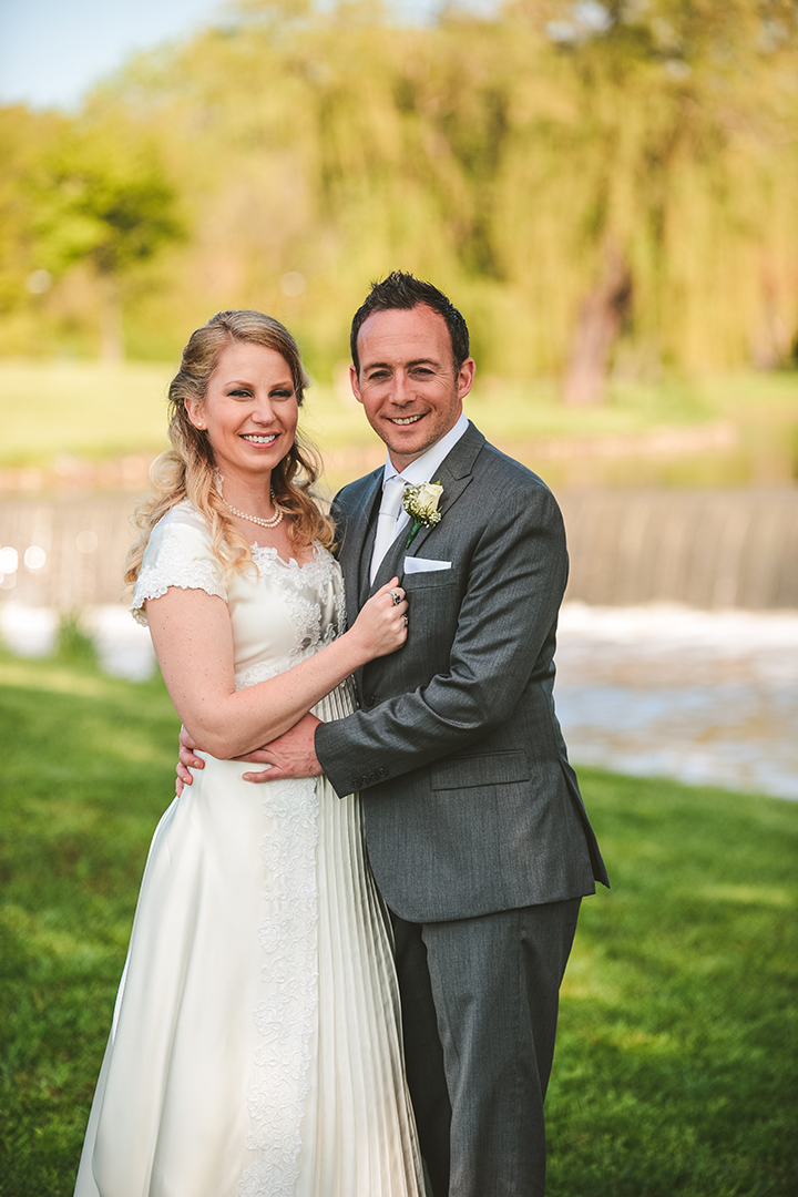 the bride and groom standing together at a park