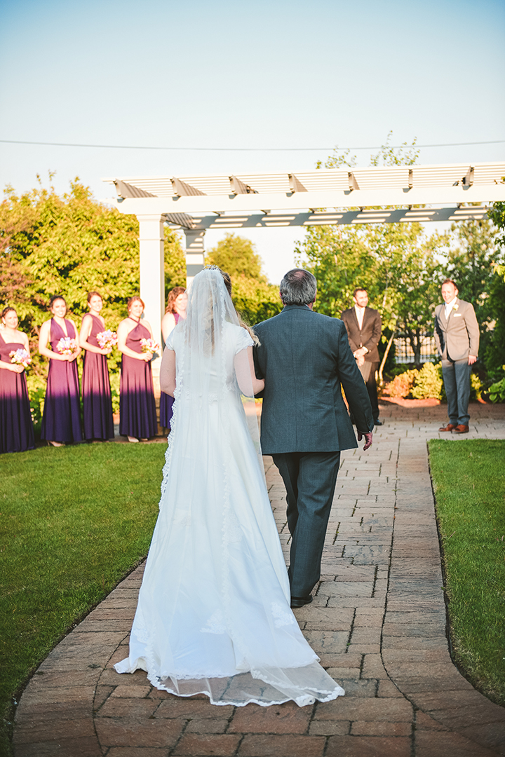 a bride and her father walking towards the waiting groom