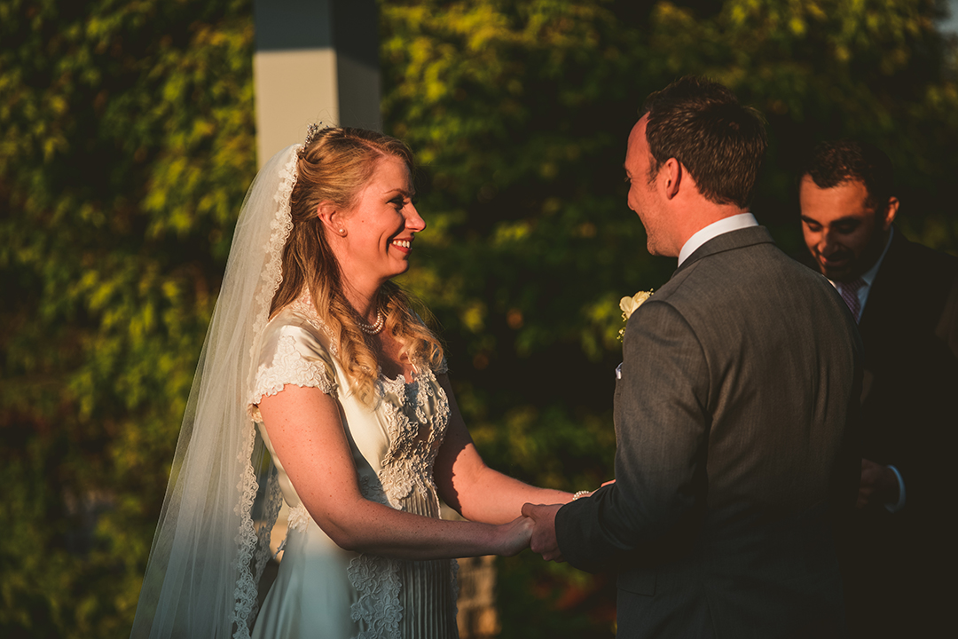 the bride smiling as she looks at her groom during an evening wedding