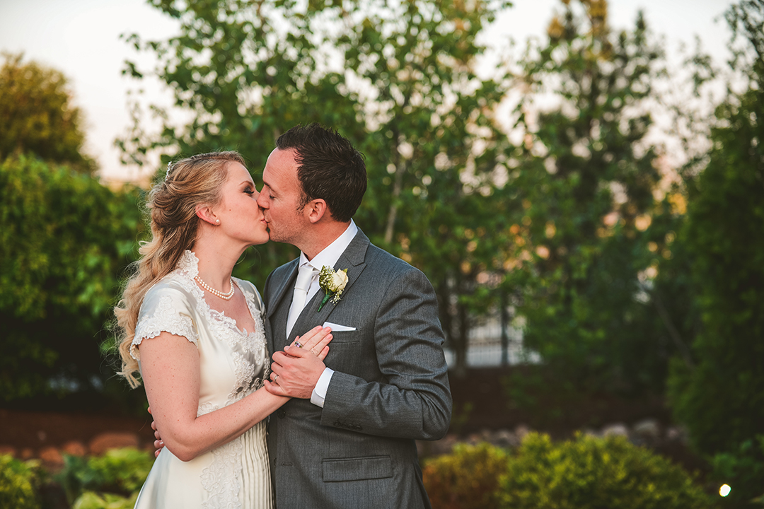 the bride and groom kissing outside in the evening