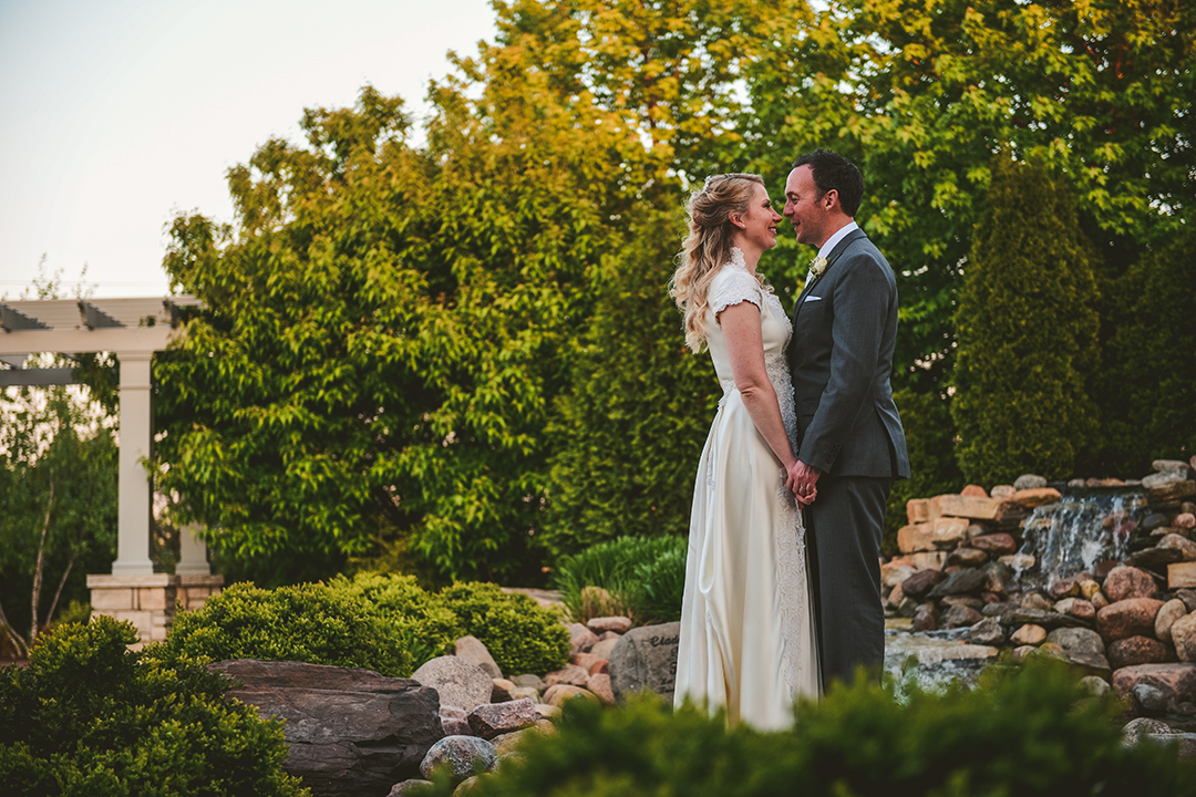 the bride and groom standing in front of evening light at Gaelic Park