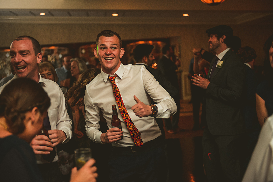 a man giving a thumbs up as he dances at a wedding reception