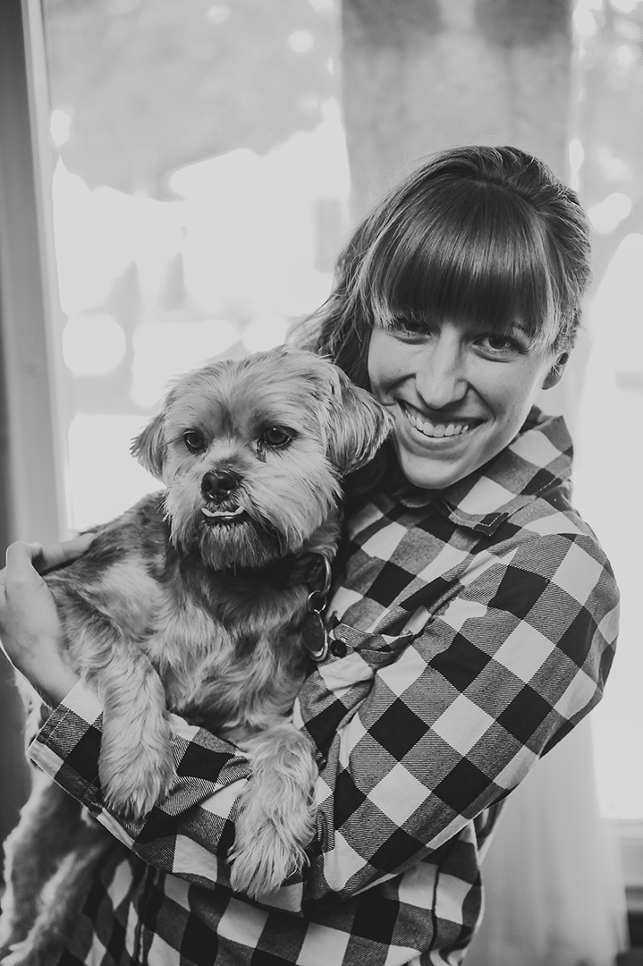 a bride holding her dog in front of her wedding dress