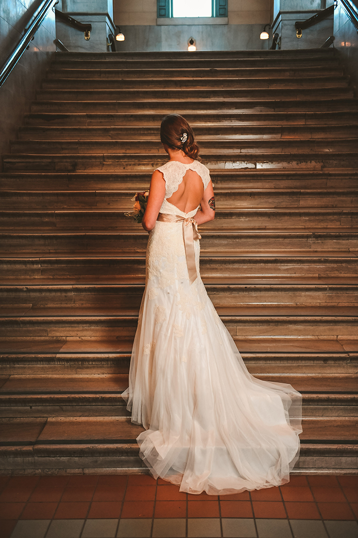 a tattooed bride standing on the Joliet Union Station steps with her flowing dress