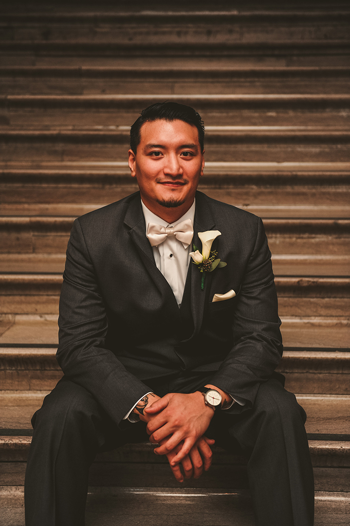 the groom sitting on the steps of the Joliet Union Station before getting married