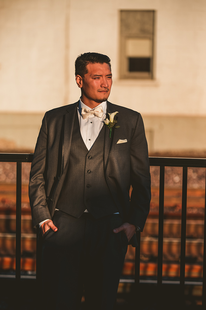 a groom standing with his hands in his pocket during golden hour