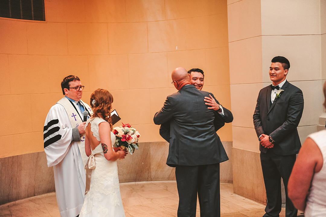 the brides father hugging the groom during their wedding