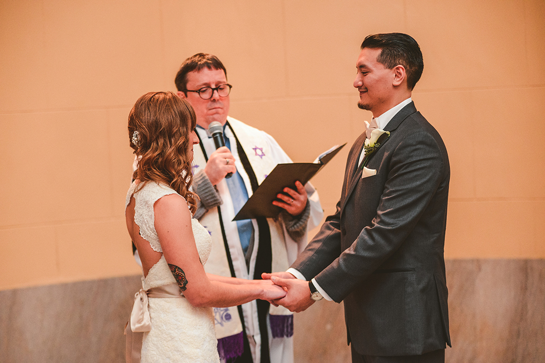 a groom holding his brides hands during their wedding ceremony