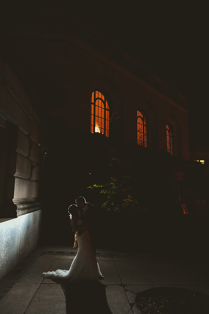 a wedding couple kissing at night in front of the Joliet Union Station