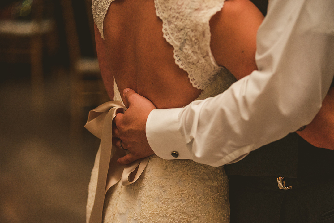 a groom with his hand on his wives back during their first dance