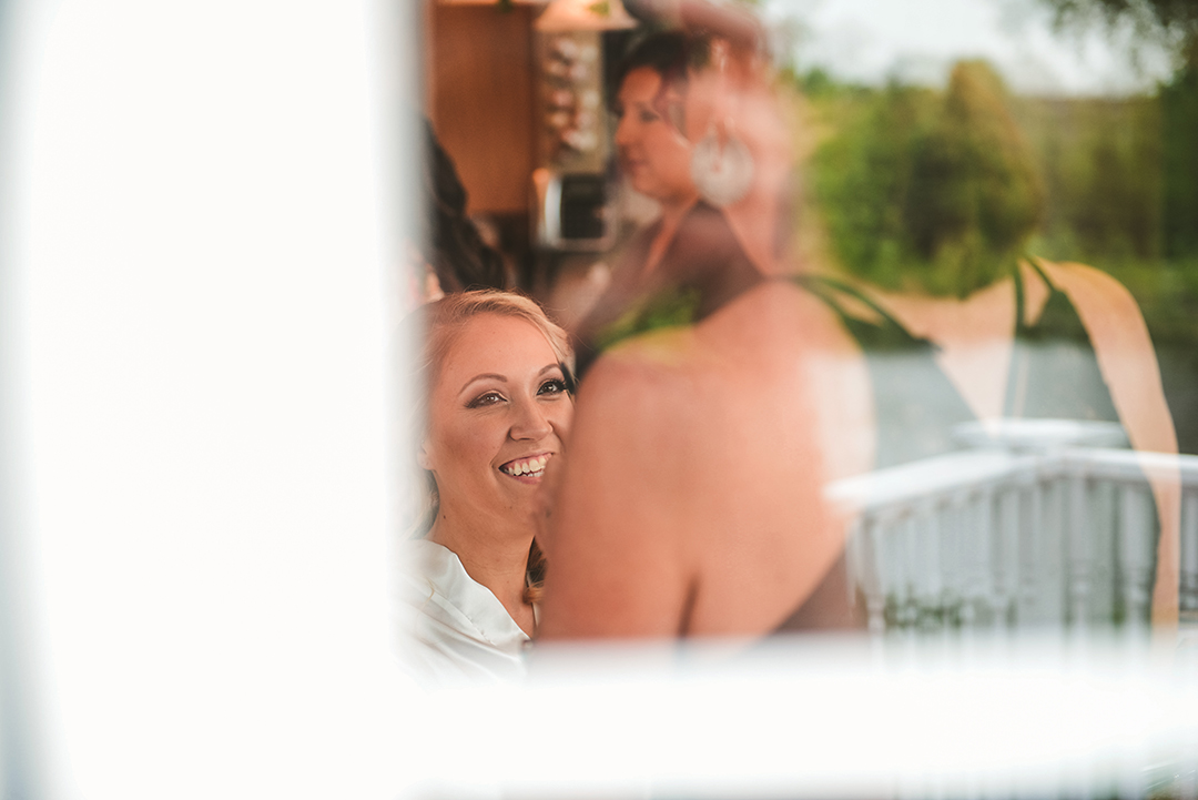 looking through a window of a bride getting her makeup done in Oak Forest