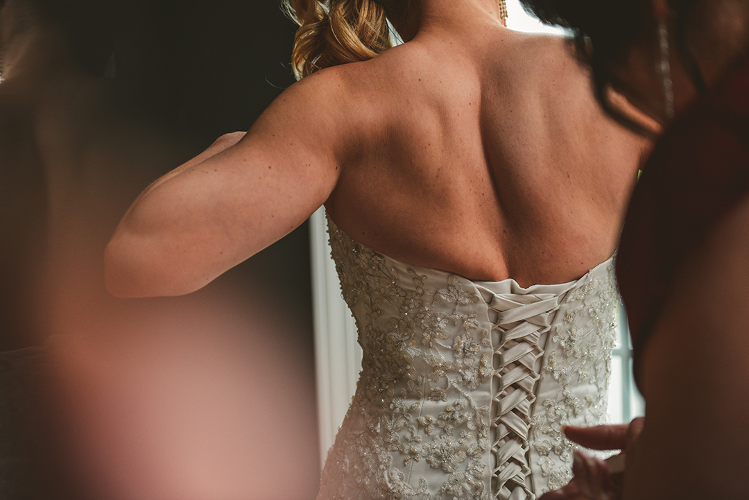 a brides mother putting on the brides dress