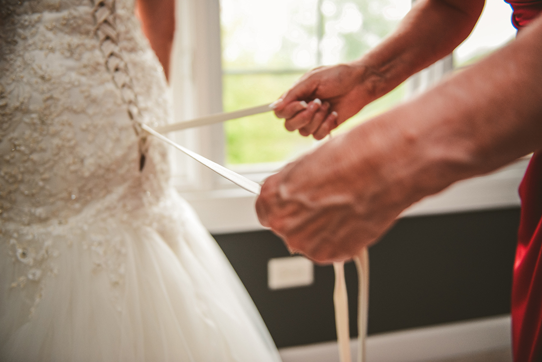 the mother of the bride lacing up her daughters dress in Oak Forest