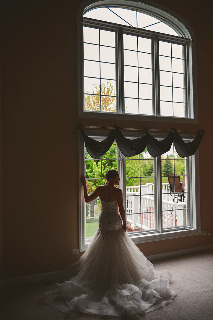 a bride standing in front of a large window with her train behind her